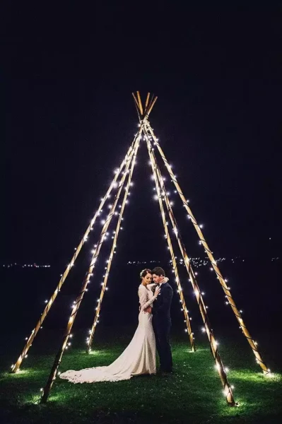 A bride and groom at night, dancing in a triangular frame of fairyl ights