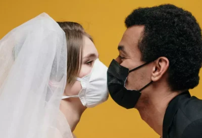 A young bride and groom kissing with covid masks