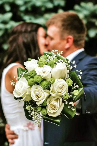 A bride and groom kissing with a bouquet of flowers in front of them
