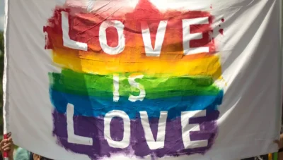 A rainbow pride banner with the caption Love is Love
